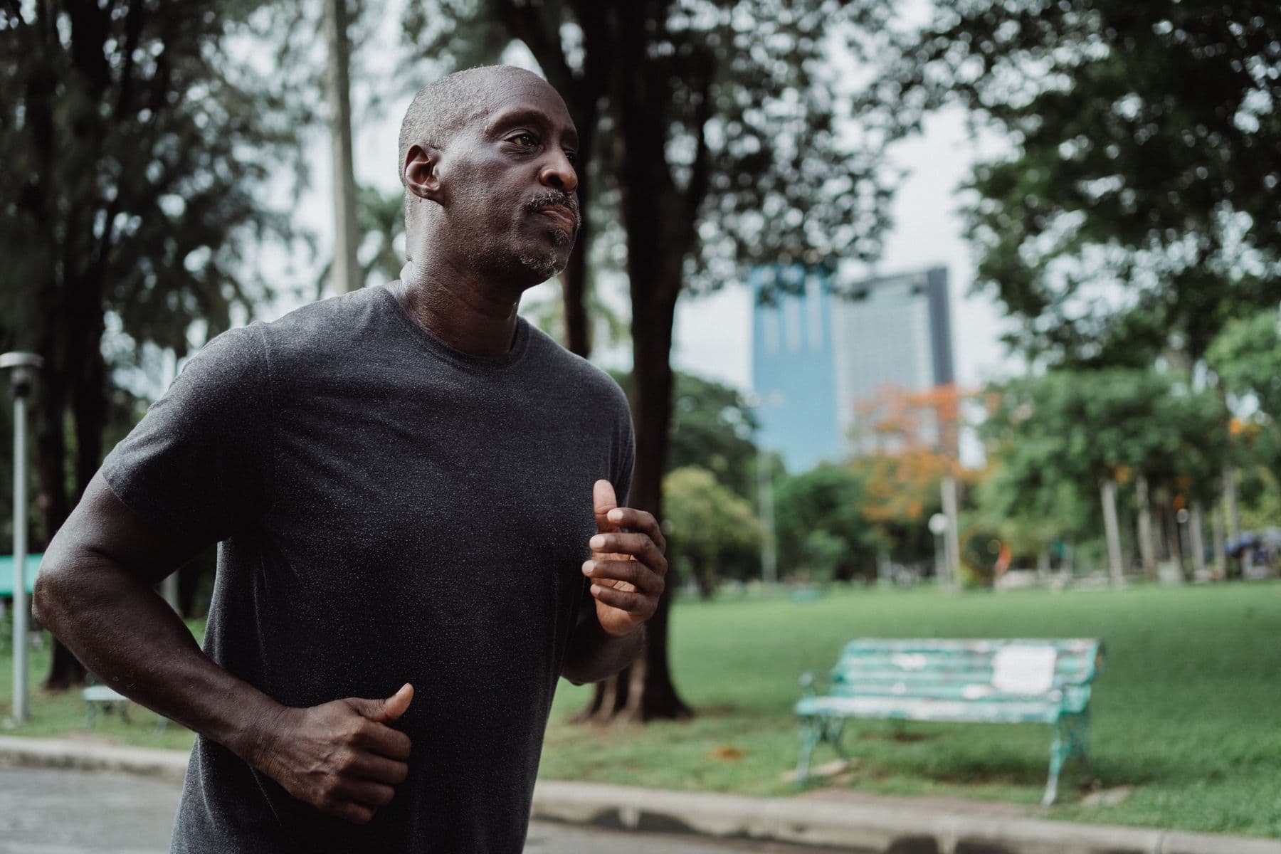 A man jogging along a leafy park path